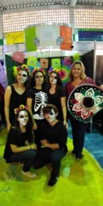 Equipe fantasiada com trajes escuros e caveiras e elementos que remetem à cultura mexicana e ao Dia de los Muertos.