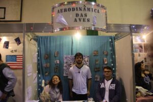 Grupo de alunos em frente ao estande "Aerodinâmica das aves"