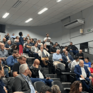 Imagem do servidor Gilherme Migliorini apresentando de pé na assembleia falando aos deputados e senadores no Fórum Parlamentar Catarinense.